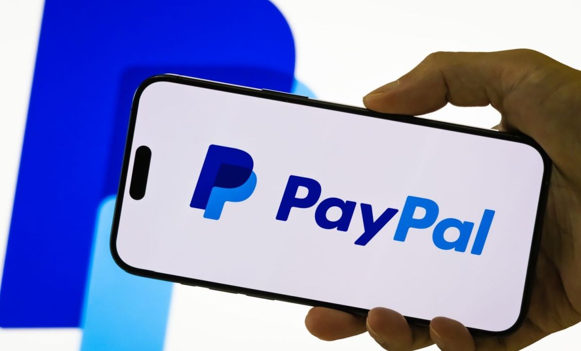 A person holding a phone with paypal app open